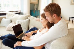 Par som kopplar av på Sofa Using Laptop Computer Together arkivbild Par som kopplar av på Sofa Using Laptop Computer Together arkivbild