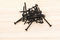 Parafusos pretos que encontram-se em uma superfície de madeira imagem de stock Parafusos pretos que encontram-se em uma superfície de madeira imagem de stock