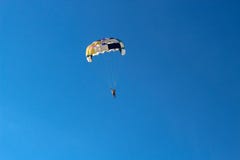 Parasailing water amusement. Beautiful bright blue sky and colorful parachute on which flies an adult man stock image Parasailing water amusement. Beautiful bright blue sky and colorful parachute on which flies an adult man stock image