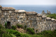 Pared de piedra vieja en el fondo de las rocas y del mar imagen de archivo libre de regalías Pared de piedra vieja en el fondo de las rocas y del mar imagen de archivo libre de regalías