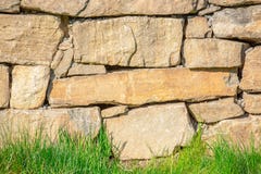 Parede de pedra atrás de um gramado da grama imagem de stock Parede de pedra atrás de um gramado da grama imagem de stock