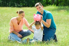 Parents avec leur fils tenant la tirelire images stock Parents avec leur fils tenant la tirelire images stock