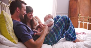 Parents In Bed Playing With Newborn Baby Daughter stock video Parents In Bed Playing With Newborn Baby Daughter stock video