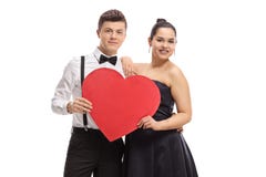 Pares adolescentes elegantemente vestidos que guardam um coração vermelho imagens de stock royalty free Pares adolescentes elegantemente vestidos que guardam um coração vermelho imagens de stock royalty free
