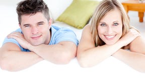 Pares afectuosos que ooking na câmera em um sofá imagem de stock Pares afectuosos que ooking na câmera em um sofá imagem de stock