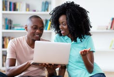 Pares afro-americanos que procuram o trabalho em linha com computador imagem de stock Pares afro-americanos que procuram o trabalho em linha com computador imagem de stock