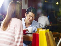 Pares asiáticos novos que conversam na cafetaria imagens de stock Pares asiáticos novos que conversam na cafetaria imagens de stock