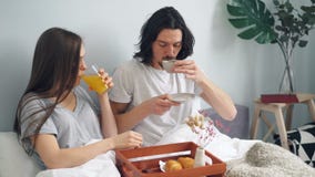 Pares bonitos que comem o café da manhã na cama em casa com pastelaria do suco de fruto do café filme Pares bonitos que comem o café da manhã na cama em casa com pastelaria do suco de fruto do café filme