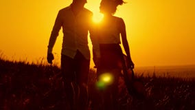 Pares cariñosos - hombre joven y muchacha hermosa que caminan en el prado de la puesta del sol - silueta almacen de video Pares cariñosos - hombre joven y muchacha hermosa que caminan en el prado de la puesta del sol - silueta almacen de video