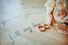 Pares de alianças de casamento em cores mornas, com as rosas amarelas de um ramalhete imagem de stock Pares de alianças de casamento em cores mornas, com as rosas amarelas de um ramalhete imagem de stock