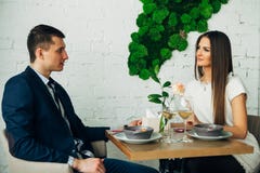 Pares de sorriso que têm o jantar e que bebem o vinho branco na data no restaurante imagem de stock Pares de sorriso que têm o jantar e que bebem o vinho branco na data no restaurante imagem de stock