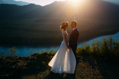 Pares felizes do casamento que ficam sobre a paisagem bonita com montanhas foto de stock royalty free Pares felizes do casamento que ficam sobre a paisagem bonita com montanhas foto de stock royalty free