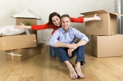 Pares felizes novos que sentam-se no assoalho que comemora junto mover-se na casa ou no apartamento liso novo fotografia de stock royalty free Pares felizes novos que sentam-se no assoalho que comemora junto mover-se na casa ou no apartamento liso novo fotografia de stock royalty free