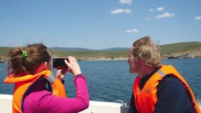 Pares jovenes en el viaje del chaleco salvavidas en un paseo del barco abajo del lago La muchacha toma la imagen con el teléfono metrajes Pares jovenes en el viaje del chaleco salvavidas en un paseo del barco abajo del lago La muchacha toma la imagen con el teléfono metrajes