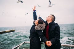 Pares jovenes felices hermosos que llevan a cabo suavemente las manos y que presentan en el embarcadero Gaviotas en el fondo Luna Fotos de archivo Pares jovenes felices hermosos que llevan a cabo suavemente las manos y que presentan en el embarcadero Gaviotas en el fondo Luna Fotos de archivo