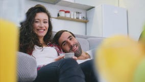 Pares jovenes que se relajan en su apartamento, mintiendo en el sofá y mirando la película metrajes Pares jovenes que se relajan en su apartamento, mintiendo en el sofá y mirando la película metrajes