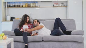 Pares jovenes que se relajan en su apartamento, mintiendo en el sofá y mirando la película almacen de metraje de vídeo Pares jovenes que se relajan en su apartamento, mintiendo en el sofá y mirando la película almacen de metraje de vídeo