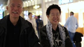 Pares mayores asiáticos felices en viaje con franquicia de la familia de la diversión del aeropuerto almacen de video Pares mayores asiáticos felices en viaje con franquicia de la familia de la diversión del aeropuerto almacen de video
