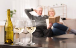 Pares mayores que miran el álbum, vino de consumición en casa imagen de archivo Pares mayores que miran el álbum, vino de consumición en casa imagen de archivo