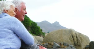 Pares mayores que se abrazan en la playa y que miran fijamente en la distancia almacen de video Pares mayores que se abrazan en la playa y que miran fijamente en la distancia almacen de video