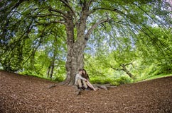 Pares milenarios que se sientan debajo de un árbol grande imágenes de archivo libres de regalías Pares milenarios que se sientan debajo de un árbol grande imágenes de archivo libres de regalías