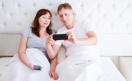 Pares, mulher e homem da Idade Média que usa o smartphone no quarto Tiro ultra largo da casa foto de stock Pares, mulher e homem da Idade Média que usa o smartphone no quarto Tiro ultra largo da casa foto de stock