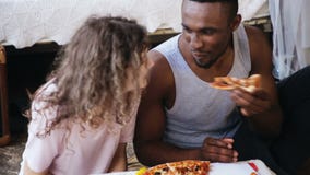 Pares multiétnicos hambrientos que comen la pizza El hombre y la mujer alimenta cada otras, se divierten durante la comida con lo Pares multiétnicos hambrientos que comen la pizza El hombre y la mujer alimenta cada otras, se divierten durante la comida con lo