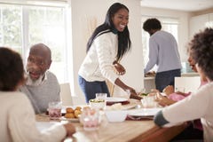 Pares negros que traen la comida a la tabla para la cena de la familia de domingo para los niños y los abuelos foto de archivo libre de regalías Pares negros que traen la comida a la tabla para la cena de la familia de domingo para los niños y los abuelos foto de archivo libre de regalías