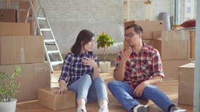 Pares novos cansados com o portátil no fundo das caixas para mover-se Pares novos cansados com o portátil no fundo das caixas para mover-se