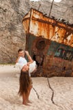 Pares novos em uma praia com naufrágio fotos de stock Pares novos em uma praia com naufrágio fotos de stock