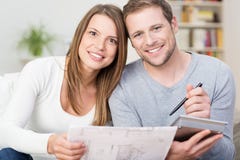 Pares novos felizes que olham um diagrama fotos de stock royalty free Pares novos felizes que olham um diagrama fotos de stock royalty free