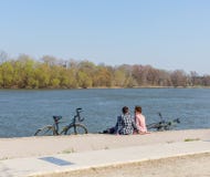 Pares novos românticos nas camisas de manta que sentam-se no banco de rio com bicicletas Conceito vivo ativo Espaço para o texto fotografia de stock royalty free Pares novos românticos nas camisas de manta que sentam-se no banco de rio com bicicletas Conceito vivo ativo Espaço para o texto fotografia de stock royalty free