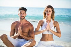 Pares que meditam ao sentar-se na costa imagem de stock Pares que meditam ao sentar-se na costa imagem de stock