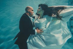 Pares rom?nticos bonitos de noivos ap?s o casamento que nadam delicadamente sob a ?gua e para relaxar foto de stock Pares rom?nticos bonitos de noivos ap?s o casamento que nadam delicadamente sob a ?gua e para relaxar foto de stock