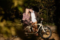 Pares rom?nticos, hombre y cierre atractivo de la muchacha junto en la bicicleta en t?ndem en parque oscuro del oto?o foto de archivo Pares rom?nticos, hombre y cierre atractivo de la muchacha junto en la bicicleta en t?ndem en parque oscuro del oto?o foto de archivo