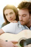 Pares românticos que sentam-se jogando o ? ao ar livre da guitarra imagens de stock Pares românticos que sentam-se jogando o ? ao ar livre da guitarra imagens de stock