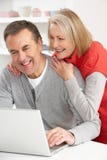 Pares sênior usando o portátil em casa imagem de stock Pares sênior usando o portátil em casa imagem de stock