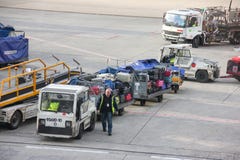 Paris, France - april 2016: Worker stacking luggage on trailer from conveyor on runway going to transportation car royalty free stock photos Paris, France - april 2016: Worker stacking luggage on trailer from conveyor on runway going to transportation car royalty free stock photos