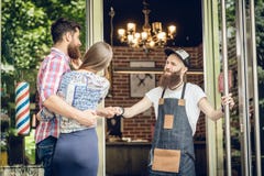 Parrucchiere fresco che dà un urto del pugno ad un cliente felice alla porta fotografie stock Parrucchiere fresco che dà un urto del pugno ad un cliente felice alla porta fotografie stock