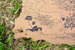 Old worlde antique style burned treasure map with dragon garding chest lying in grass stock photo Old worlde antique style burned treasure map with dragon garding chest lying in grass stock photo
