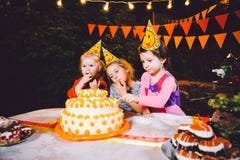 Parti för födelsedag för barn` s Tre gladlynta barnflickor på tabellen som äter kakan med deras händer och suddar deras framsida royaltyfria foton Parti för födelsedag för barn` s Tre gladlynta barnflickor på tabellen som äter kakan med deras händer och suddar deras framsida royaltyfria foton