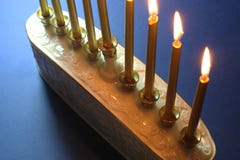 Partial view of a white ceramic menorah with gold candles against a blue background, backlit royalty free stock photography Partial view of a white ceramic menorah with gold candles against a blue background, backlit royalty free stock photography