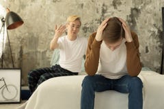 Partner omosessuali internazionali che hanno conversazione mentre spendendo tempo nella camera da letto moderna del sottotetto immagine stock Partner omosessuali internazionali che hanno conversazione mentre spendendo tempo nella camera da letto moderna del sottotetto immagine stock
