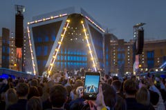 Hand with smartphone recording video / photo at live music concert, silhouettes of crowd in front of bright stage lights. stock images Hand with smartphone recording video / photo at live music concert, silhouettes of crowd in front of bright stage lights. stock images