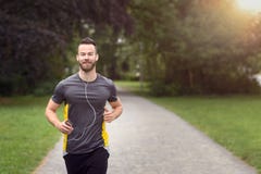 Passa den skäggiga unga mannen som joggar till och med en parkera royaltyfri bild Passa den skäggiga unga mannen som joggar till och med en parkera royaltyfri bild