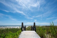 Passaggio pedonale di legno alla spiaggia sotto un cielo luminoso di estate fotografia stock libera da diritti Passaggio pedonale di legno alla spiaggia sotto un cielo luminoso di estate fotografia stock libera da diritti