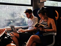 Passagiere des jungen Mannes und des Mädchens auf Zug ein Buch lesend stockfotos Passagiere des jungen Mannes und des Mädchens auf Zug ein Buch lesend stockfotos
