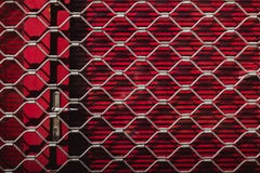 Passe a textura de uma grade de aço em obturadores vermelhos na porta Fundo vermelho imagens de stock royalty free Passe a textura de uma grade de aço em obturadores vermelhos na porta Fundo vermelho imagens de stock royalty free