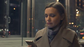 Passeio fêmea atrativo na noite com o smartphone nas mãos, lendo o e-mail vídeos de arquivo Passeio fêmea atrativo na noite com o smartphone nas mãos, lendo o e-mail vídeos de arquivo
