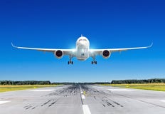 Passenger airplane with bright landing lights landing at in good clear weather with a blue sky on a runway. royalty free stock image Passenger airplane with bright landing lights landing at in good clear weather with a blue sky on a runway. royalty free stock image